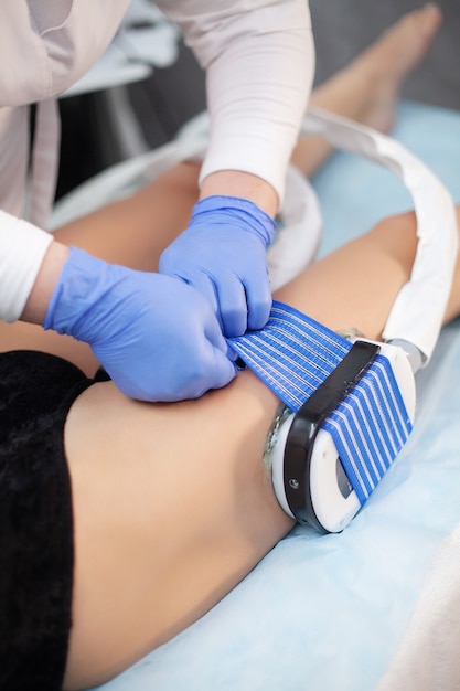 La procédure de myostimulation sur les jambes d'une femme dans un salon de beauté.