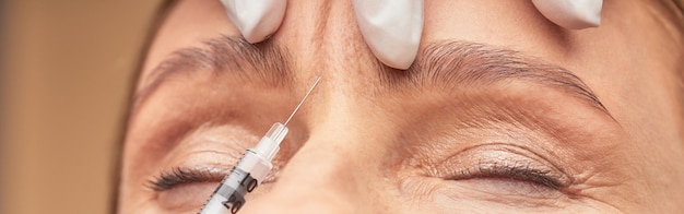 Procédures anti-vieillissement prise de vue rapprochée d'une esthéticienne en gants de protection faisant une injection cosmétique dans