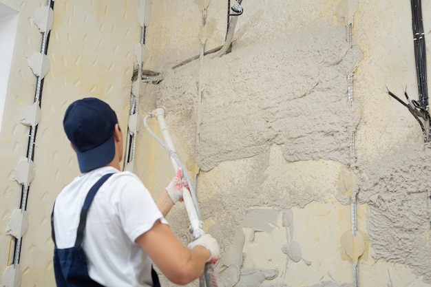 Le processus d'application de plâtre sur les murs à l'intérieur d'un bâtiment à la machine