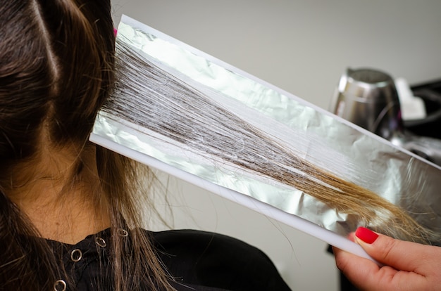 Photo processus d'application de poudre décolorante sur les cheveux des clients et enveloppement dans la feuille.