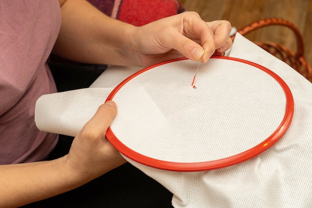 Processus de broderie au point de croix sur tissu dans un cadre avec les mains