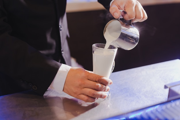 Photo processus consistant à verser de la mousse de lait dans la préparation du café.