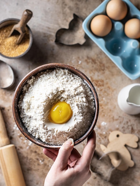 Le processus de cuisson de la farine de cuisson dans un bol avec le jaune d'oeuf levant dans la main les oeufs le sucre le lait Vue de dessus