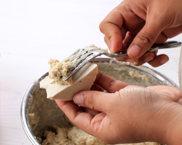 Processus de cuisson Tofu farci avec pâte de poisson Faire Baso Tahu Goreng Batagor ou Siomay Bandung Nourriture de rue populaire en Indonésie Une main de femme à l'aide d'une fourchette