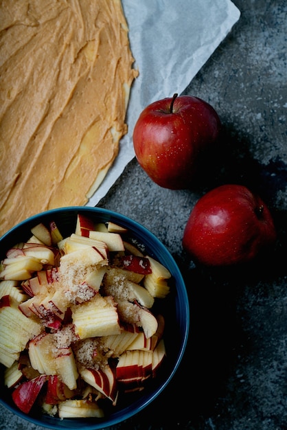 Photo processus de cuisson des tourbillons de pommes. pâte farcie au beurre d'arachide et pommes coupées avec cassonade et deux pommes. vue de dessus. mise à plat