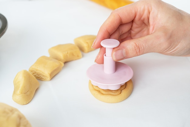 Le processus de fabrication de biscuits avec des formes en forme de fleurs un rouleau à pâtisserie et un plateau le concept de cuisson à la maison
