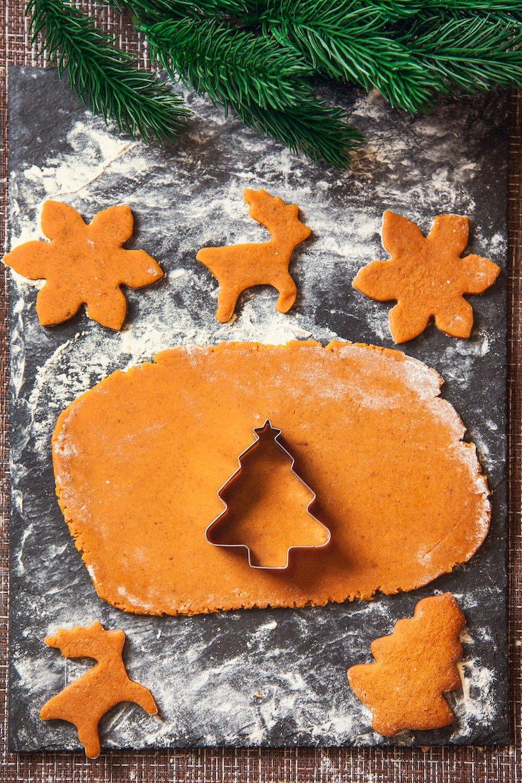 Photo le processus de fabrication des biscuits de noël au gingembre. un moule en forme d'arbre de noël sur une pâte crue pour des biscuits de pain d'épice.
