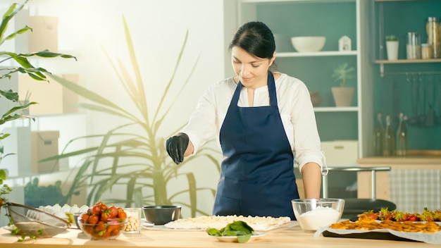 Le processus de fabrication de la confiserie. Le chef saupoudre le gâteau de noix. Intérieur de cuisine moderne et confortable. Concept de fabrication de confiseries et petites entreprises.