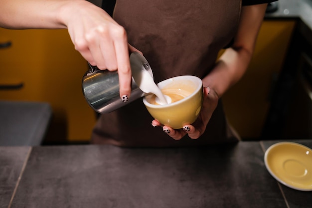 Processus de fabrication du café Barista versant du lait chaud dans une tasse de café