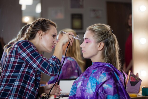 Le processus de fabrication de maquillage moderne à l'aérographe. Maquilleuse crée et se concentre