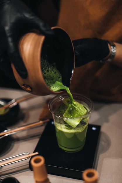 Processus de fabrication de thé vert japonais Matcha Mains féminines versant du matcha dans une tasse en plastique