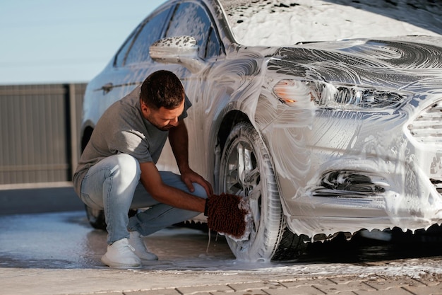 Processus de lavage de l'automobile L'homme est avec sa voiture à l'extérieur