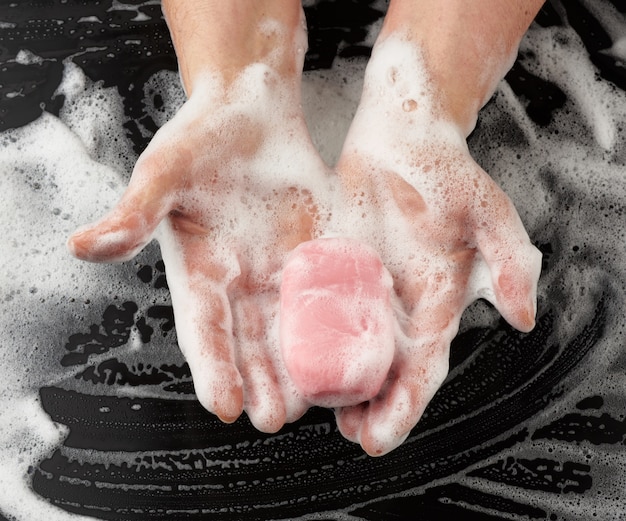 Processus de lavage des mains avec du savon rose, parties du corps en mousse blanche