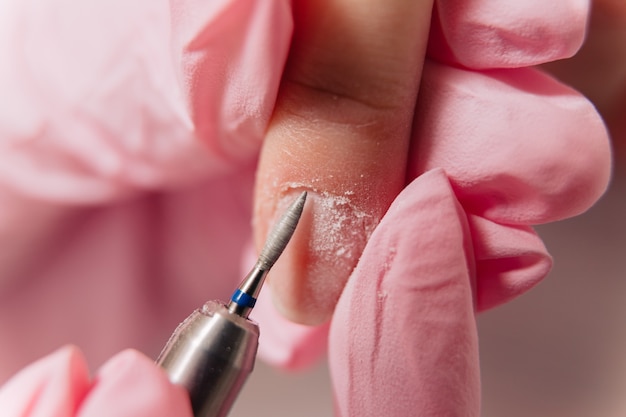 Processus de manucure. Le maître polit l'ongle à l'aide d'une machine automatisée. Dissolvant pour percer.