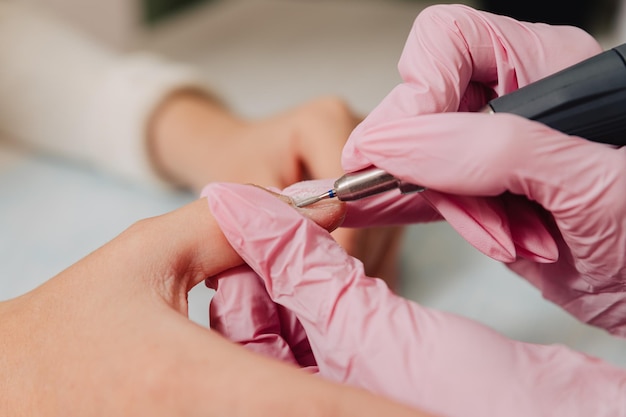 Photo processus de manucure le maître polit l'ongle à l'aide d'une machine automatisée dissolvant de vernis