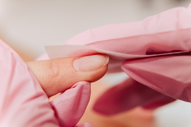 Processus de manucure. Traiter l'ongle avec un antiseptique pour la guérison et la désinfection. Le maître essuie l'ongle avec une serviette.