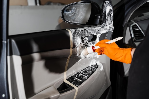 Processus de nettoyage à la mousse et au détergent avec brosse panneau de carte de porte de voiture Service d'esthétique automobile Travailleur dans le service de nettoyage lavage intérieur de l'auto des clients