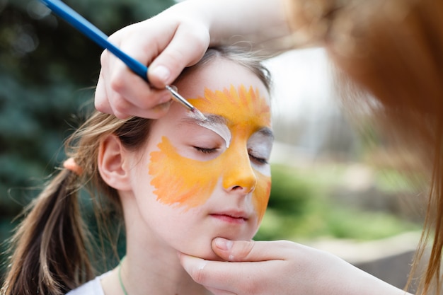 Processus de peinture enfant sur le visage de la fille