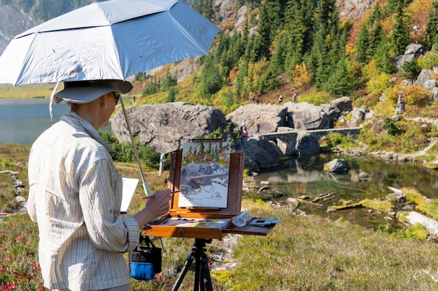 Processus de peinture en plein air, étudiants adultes dans le parc avec des chevalets de peinture et des toiles pendant la leçon