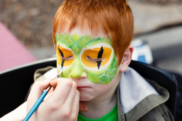 Photo processus de peinture de visage d'enfant sur garçon rousse