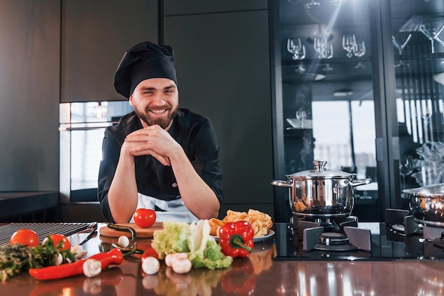 Processus de préparation Jeune chef cuisinier professionnel en uniforme travaillant dans la cuisine