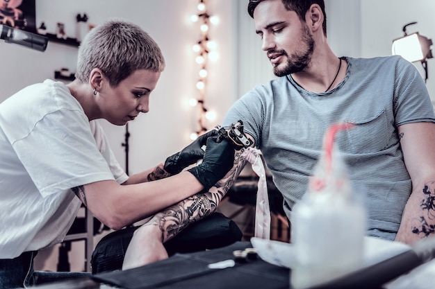 Processus De Récupération. Maître Extraordinaire Concentré Faisant La Coloration Pour Les Tatouages Passés Remplissant Les Contours Noirs