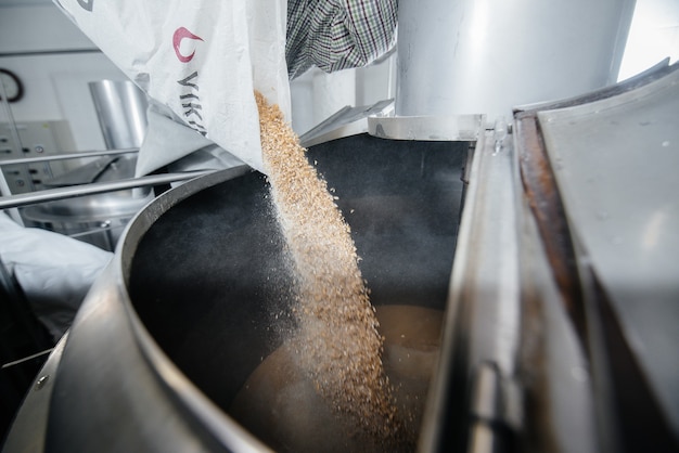 Photo le processus de remplissage du malt dans un récipient pour faire de la bière. brasserie traditionnelle.