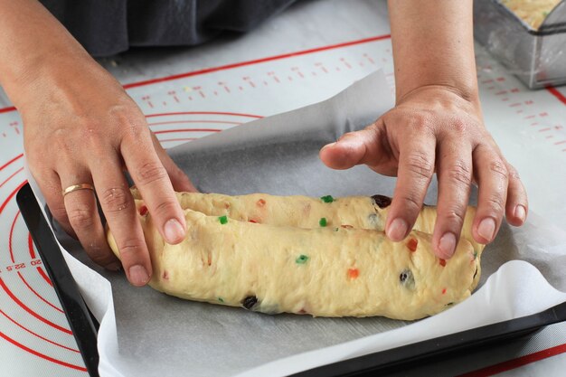 Processus de rouler la pâte crue du gâteau allemand Stollen de Noël dans la cuisine