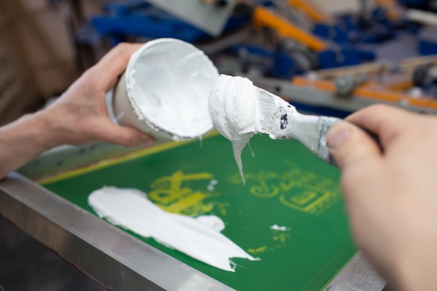 Processus de sérigraphie en sérigraphie à l'usine de vêtements. Application de peinture sur les peintures de couleur de cadre, de raclette et de plastisol