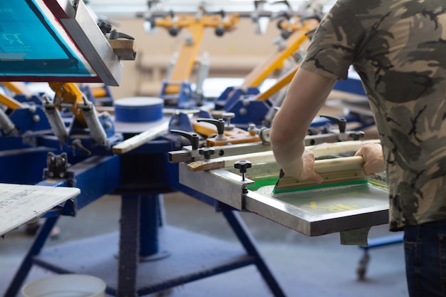 Processus de sérigraphie sérigraphique à l'usine de vêtements. Peintures couleur cadre, raclette et plastisol