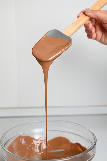 Le processus de tempérer le chocolat et de faire des chocolats Chef pâtissier utilisant une spatule tempérant le chocolat fondu