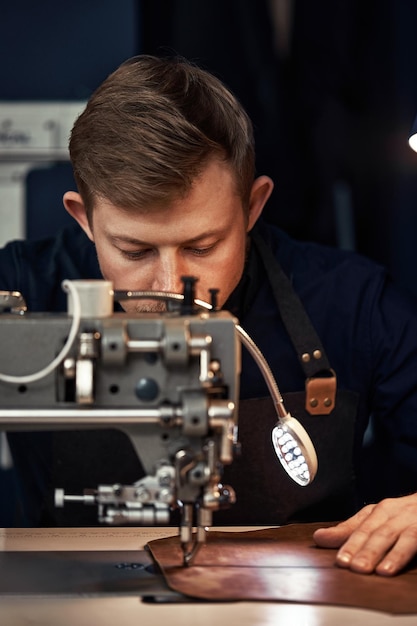 Processus de travail d'un artisan du cuir Tanner ou skinner coud du cuir sur une machine à coudre spéciale close upworker cousant sur la machine à coudre