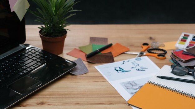 Processus de travail de créateur de mode. bureau avec des échantillons de couleurs, des croquis de bloc-notes et des fournitures sur la table