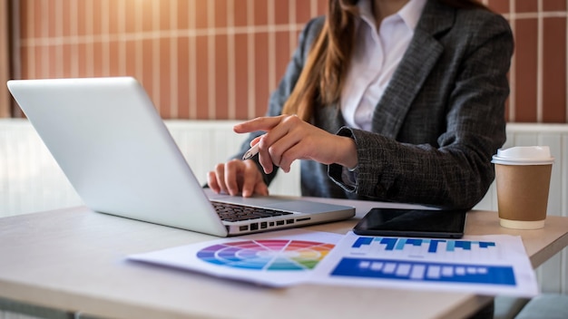 Processus de travail dans un bureau moderne Jeune femme gestionnaire de compte travaillant à table avec un nouveau projet d'entreprise Clavier de saisie à l'aide d'un ordinateur portable contemporain