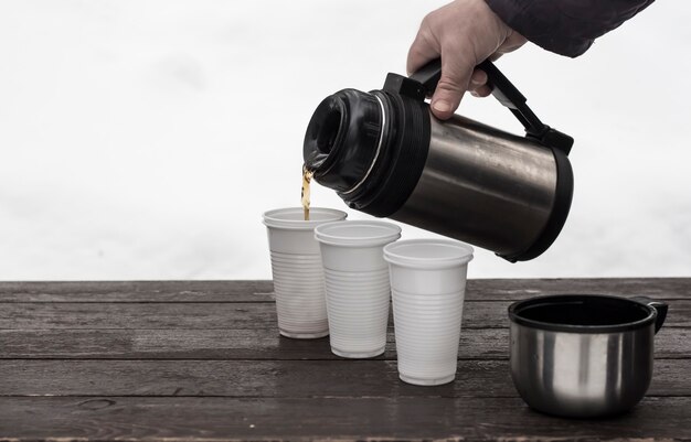 Le processus de verser du café dans des verres jetables en hiver dans la nature.