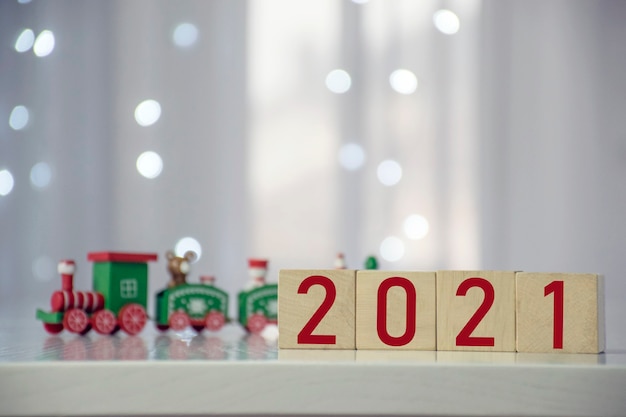 Prochainement Numéro du Nouvel An sur bloc de cube en bois avec train de Noël coloré et lumières floues bokeh