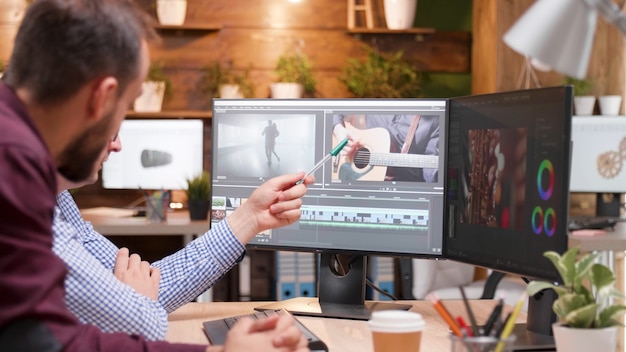 Producteur vidéaste éditant la production cinématographique discutant du graphisme du film avec un collègue photographe travaillant dans une entreprise de démarrage de créativité. Homme d'éditeur concentré développant des séquences numériques. Industrie numérique