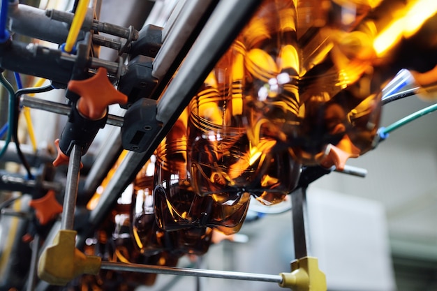 Production industrielle de bouteilles en plastique pour boissons à faible teneur en alcool, sodas et huile de tournesol. Bouteilles en PET vides de couleur brune sur fond d'équipement moderne.