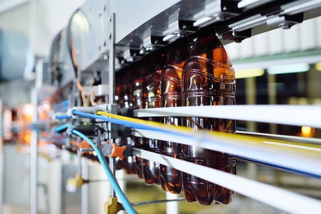 Production Industrielle De Bouteilles En Plastique Pour Boissons à Faible Teneur En Alcool, Sodas Et Huile De Tournesol. Bouteilles En Pet Vides De Couleur Brune Sur Fond D'équipement Moderne.