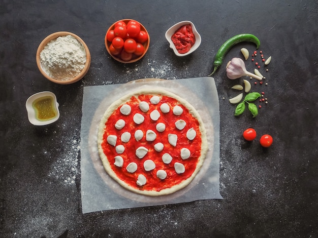 Production de pizza italienne Margarita. Stade de production. Sauce tomate, mozzarella et tomates