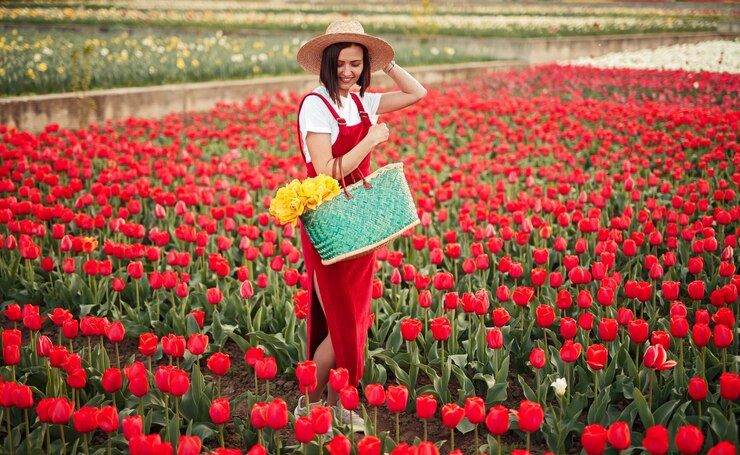 Photo la productrice debout sur le terrain avec des tulipes rouges