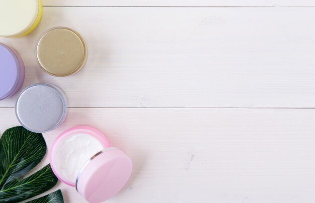 Produit cosmétique et de soin de la peau et feuilles vertes sur une table en bois blanc