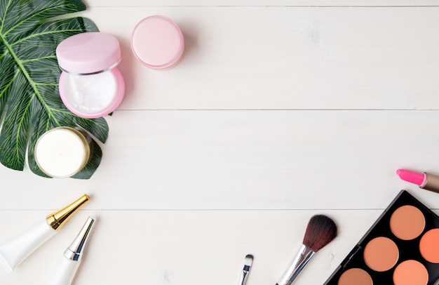 Produit cosmétique et de soin de la peau et feuilles vertes sur une table en bois blanc