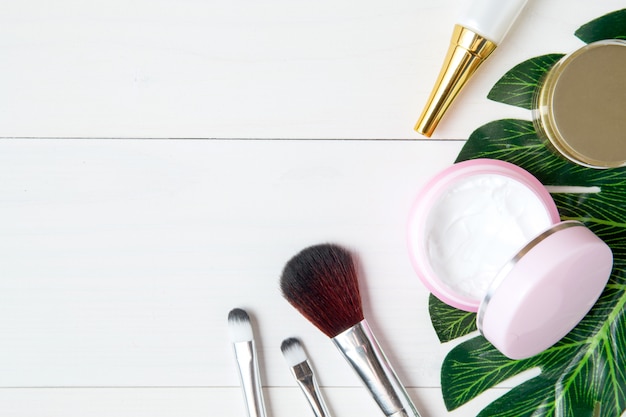 Photo produit cosmétique et de soin de la peau et feuilles vertes sur une table en bois blanc