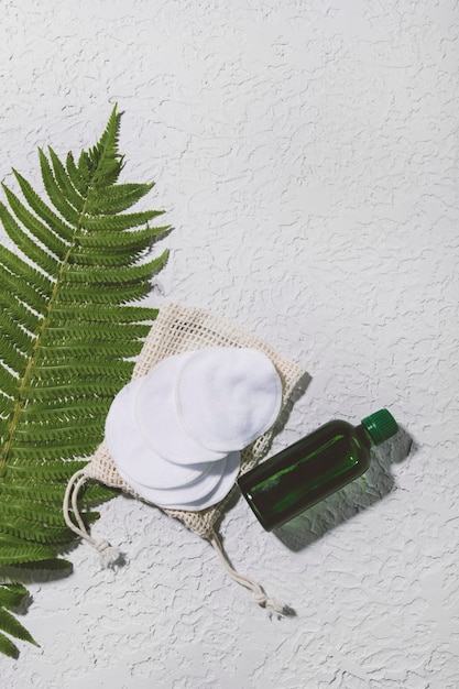 Produit de soin de la peau naturel dans une bouteille en verre avec compte-gouttes avec des feuilles vertes sur fond de concert