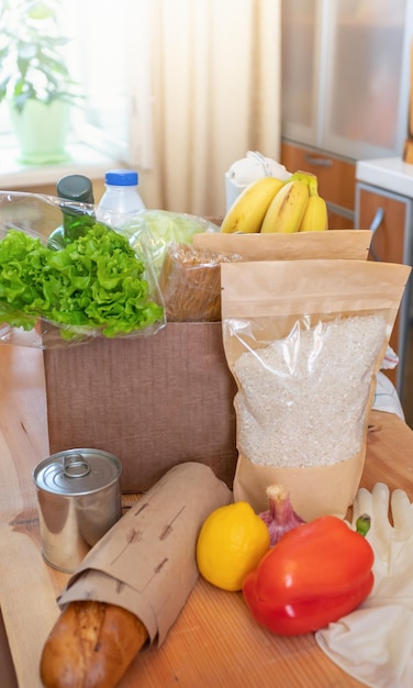 Produits alimentaires frais dans des boîtes en carton et sur une table en bois à l'intérieur de la cuisine livraison sûre