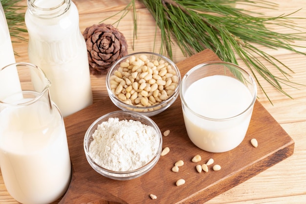 Produits à base de noix de cèdre Verre et bouteilles avec noix de lait et poudre sur table en bois Mise au point sélective