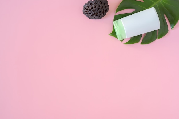 Produits bio de soins de la peau du corps avec des feuilles vertes et de la noix de coco sur fond rose disposition tendance