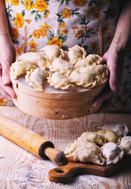 Produits de boulangerie traditionnels ukrainiens - Fabrication de pierogies par des mains féminines. Style rustique. Photo rétro