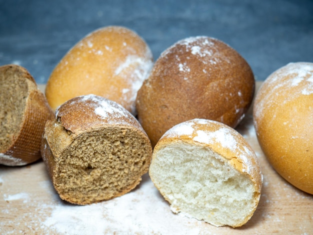 Produits de boulangerie en tranches Table dans la boulangerie Petits pains sur une planche à découper Petits pains de seigle et de blé Produits à base de farine de blé et de farine de seigle de première qualité